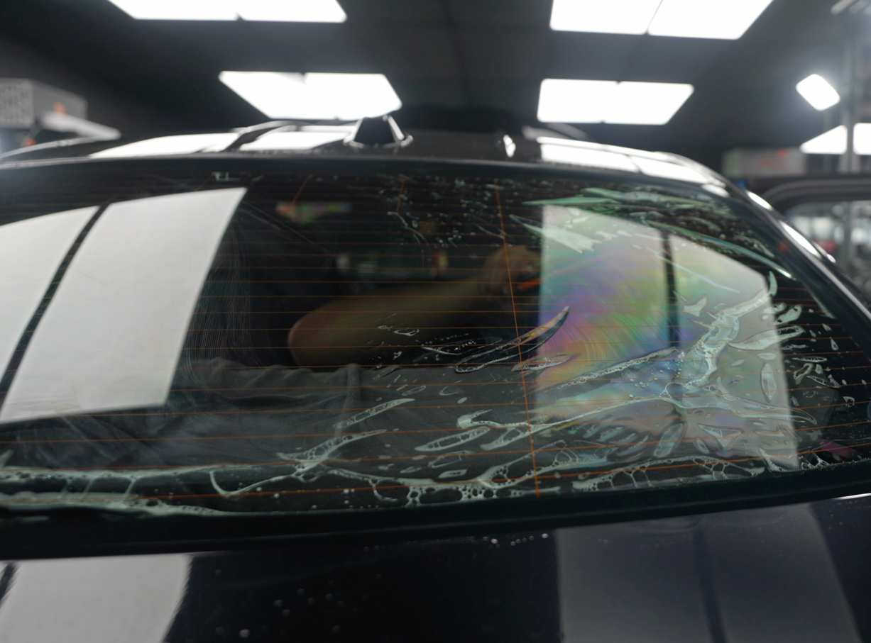 A person is installing a rear view mirror on a car.