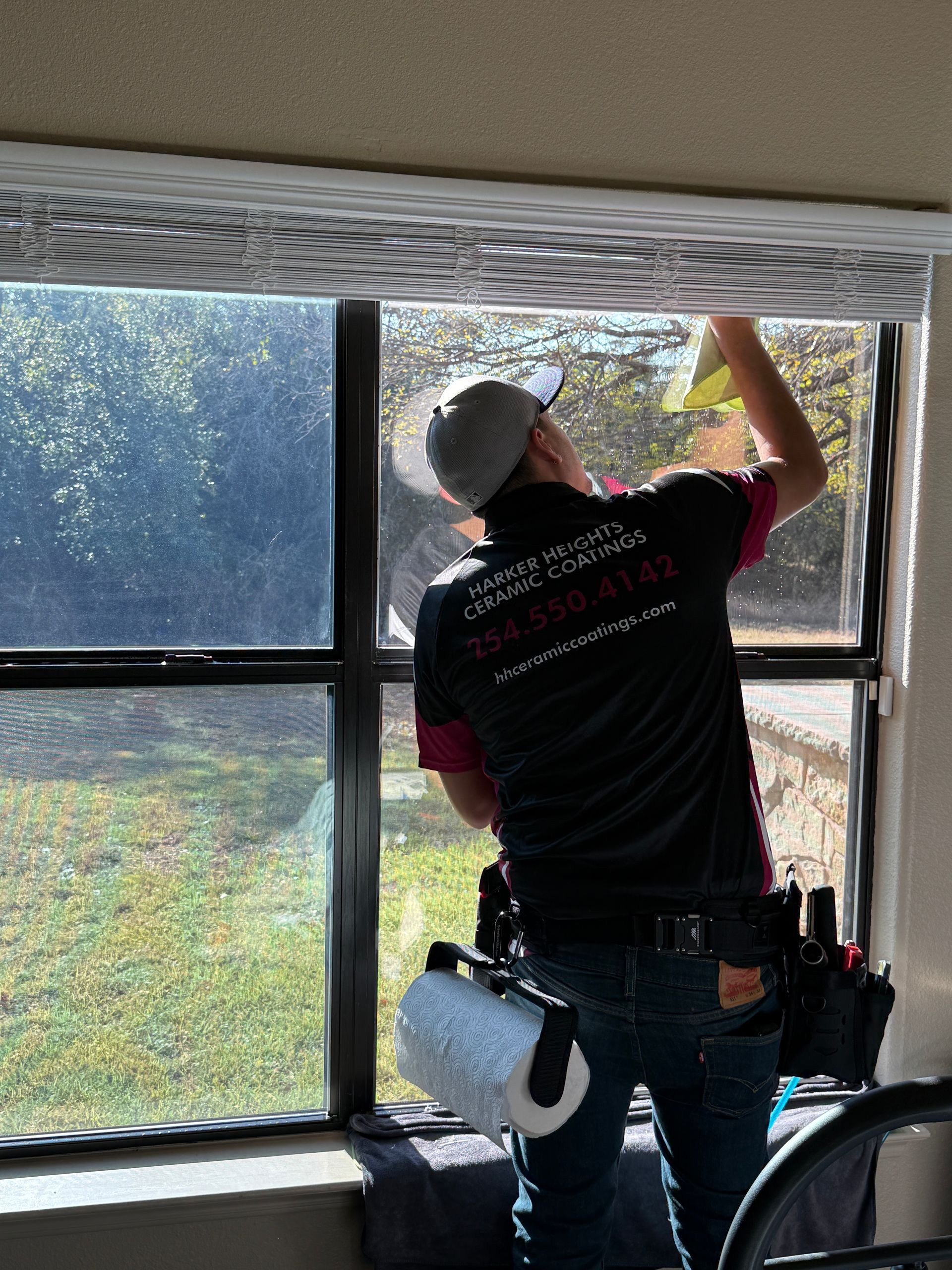 A person is applying tinted window film to a car window.