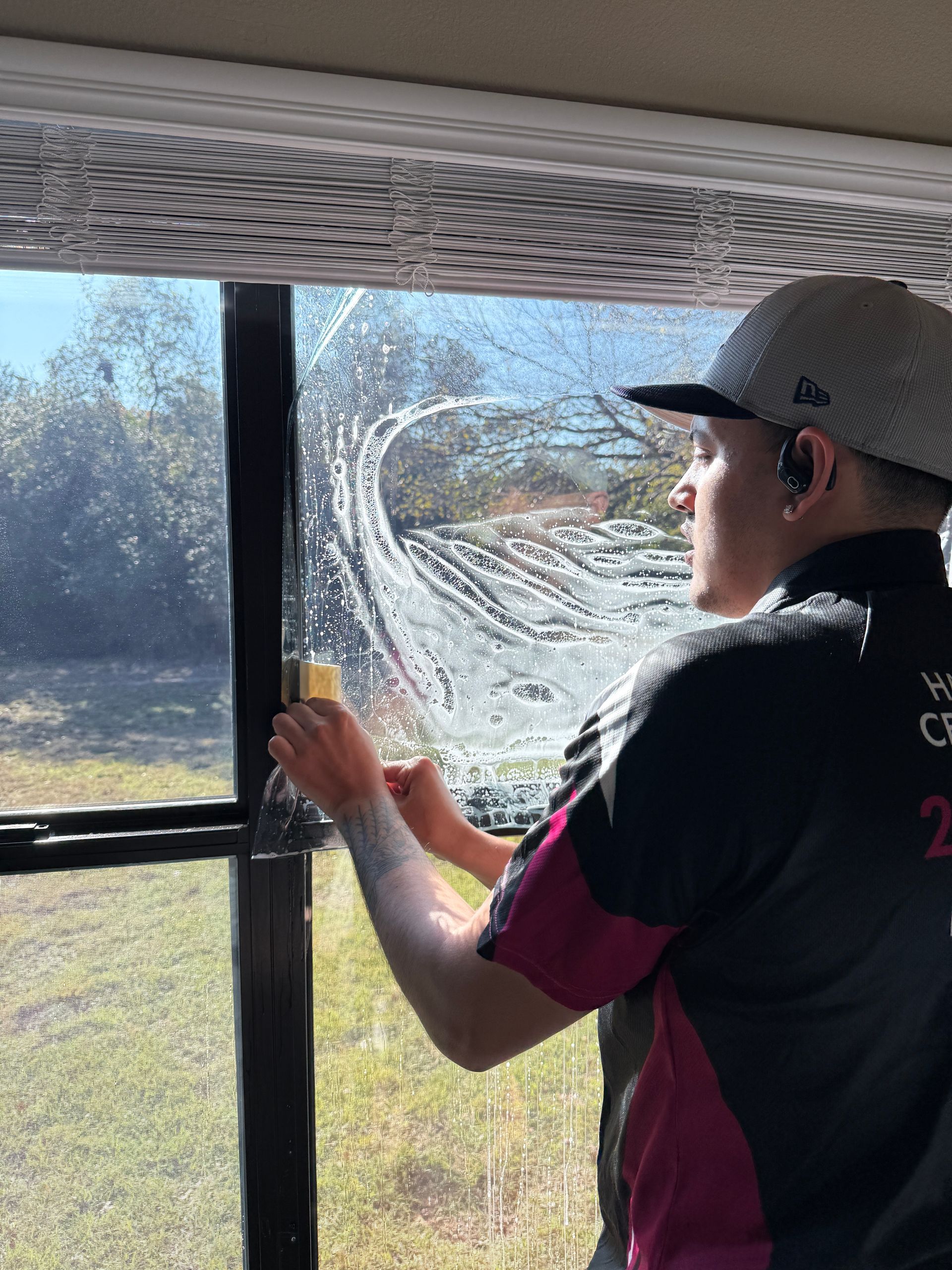 A man is cleaning a white car with a blue cloth.