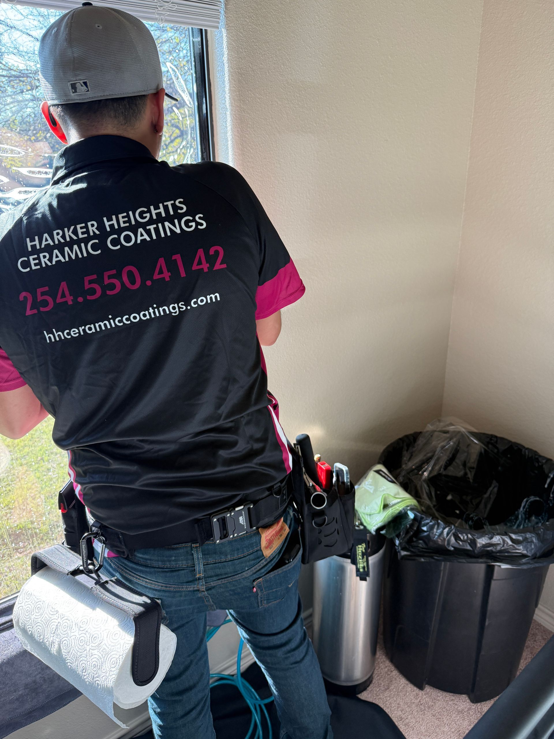 A man is cleaning a white car with a blue cloth.