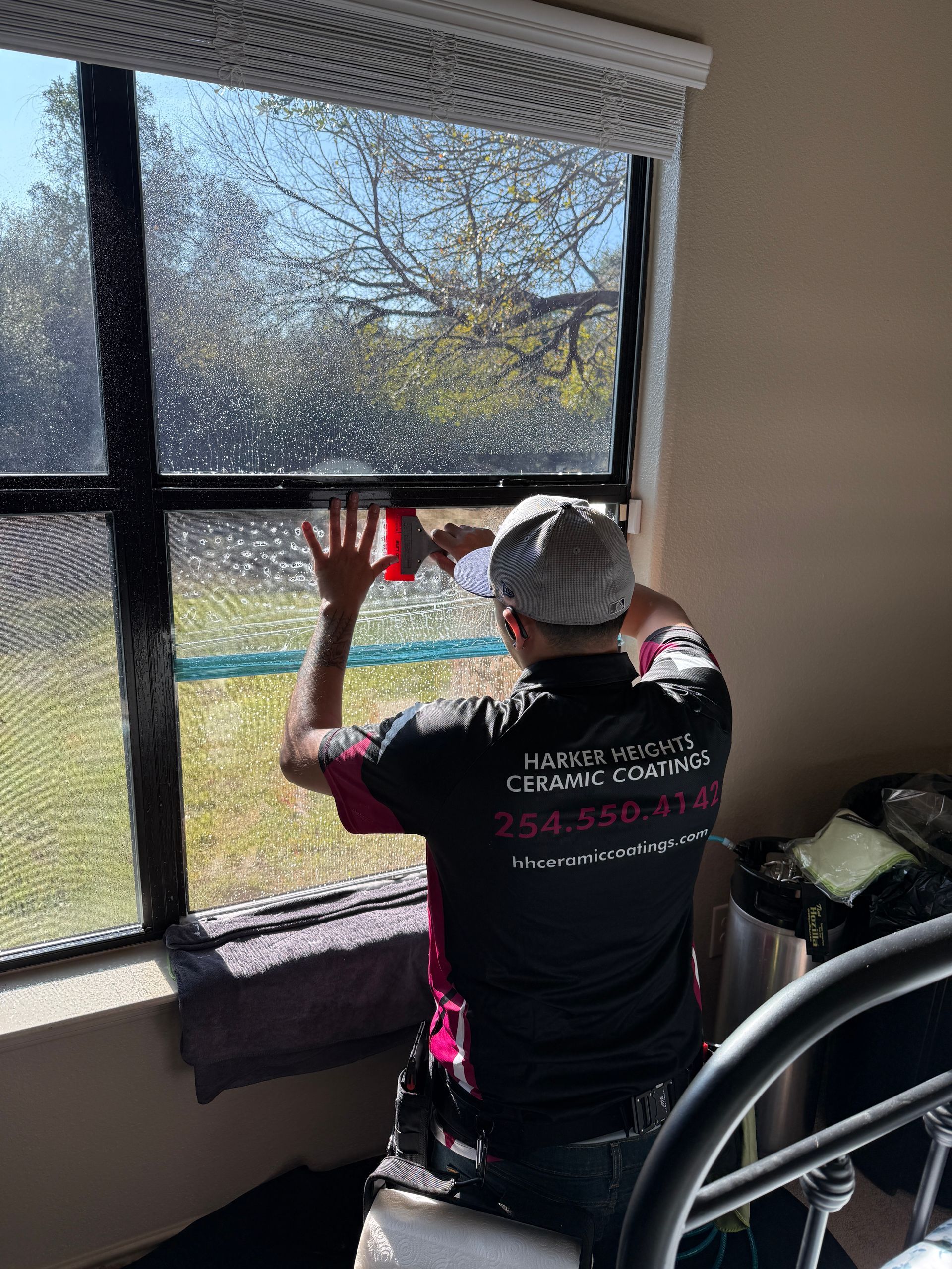 A person is applying tinted window film to a car window.