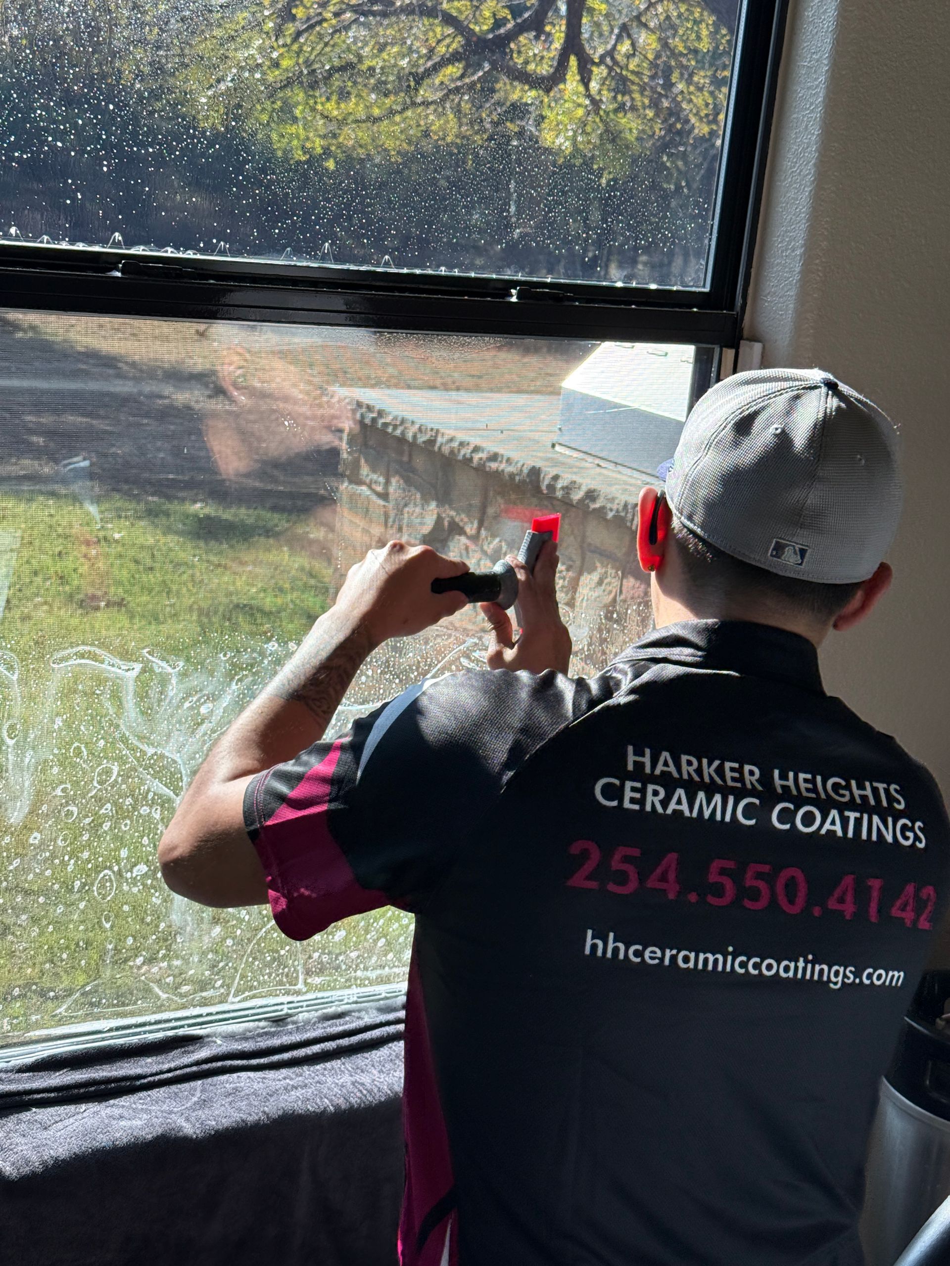 A person is cleaning a car window with a squeegee.
