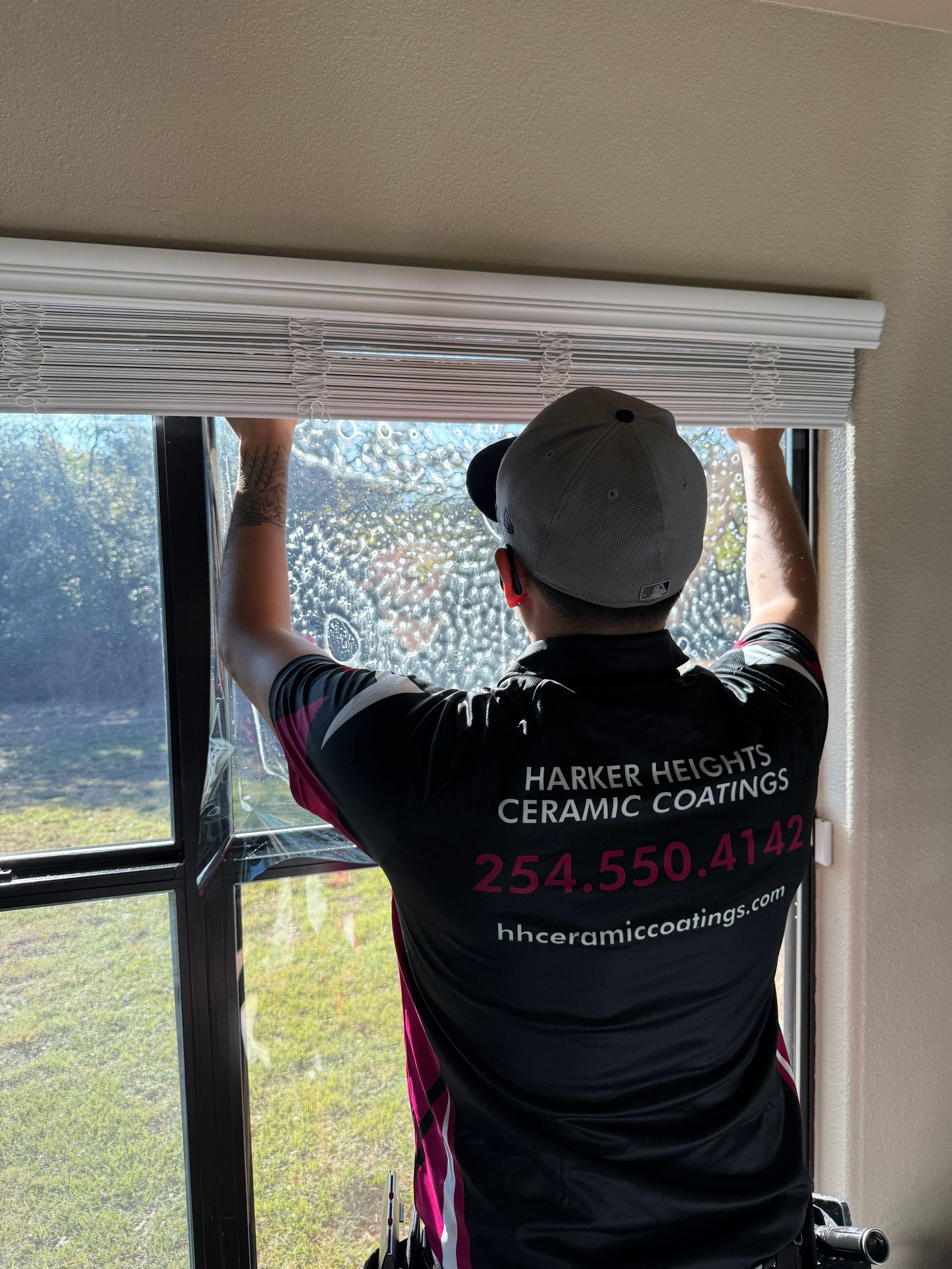 A man is cleaning a white car with a blue cloth.
