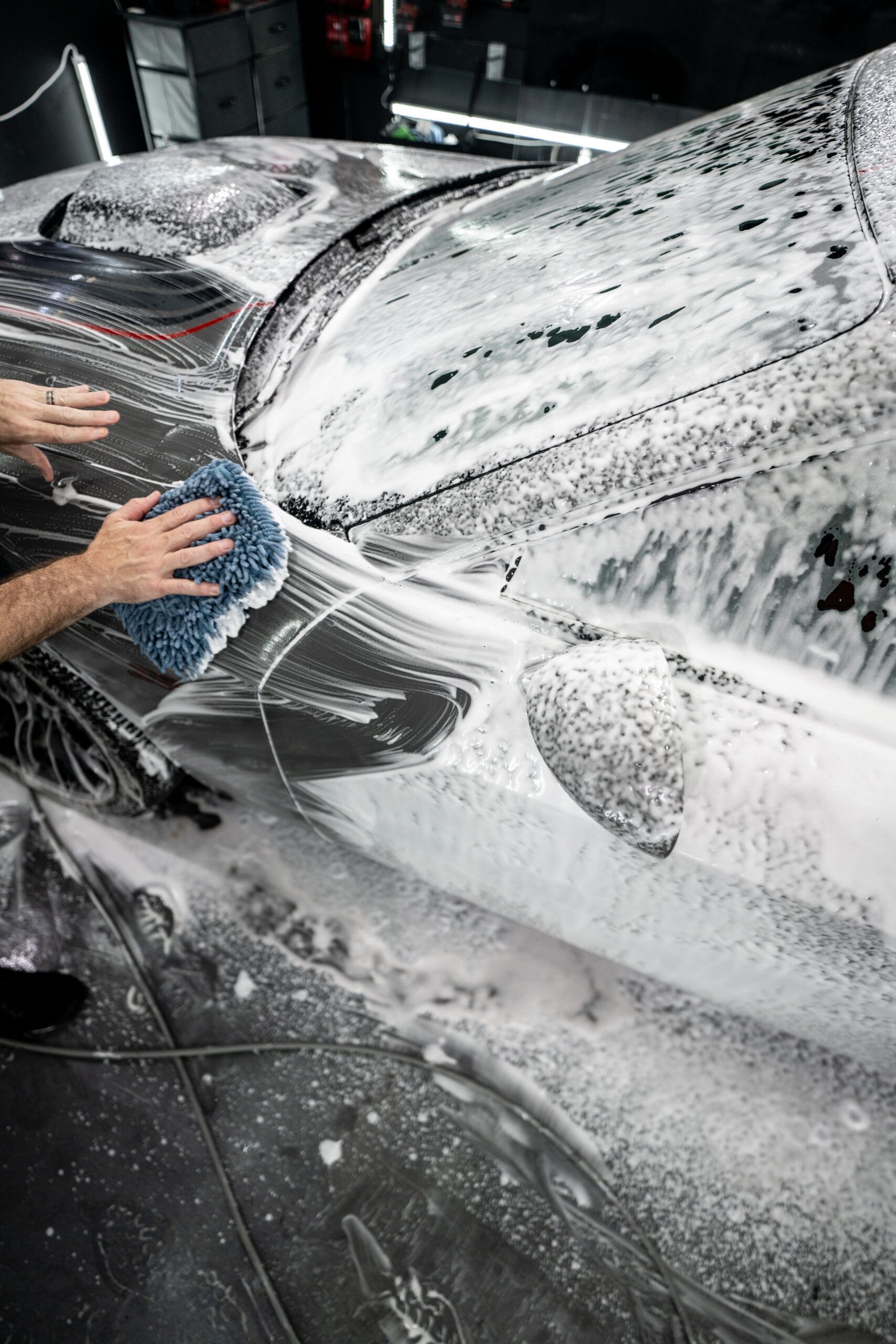 A man is washing a car with a sponge and foam.