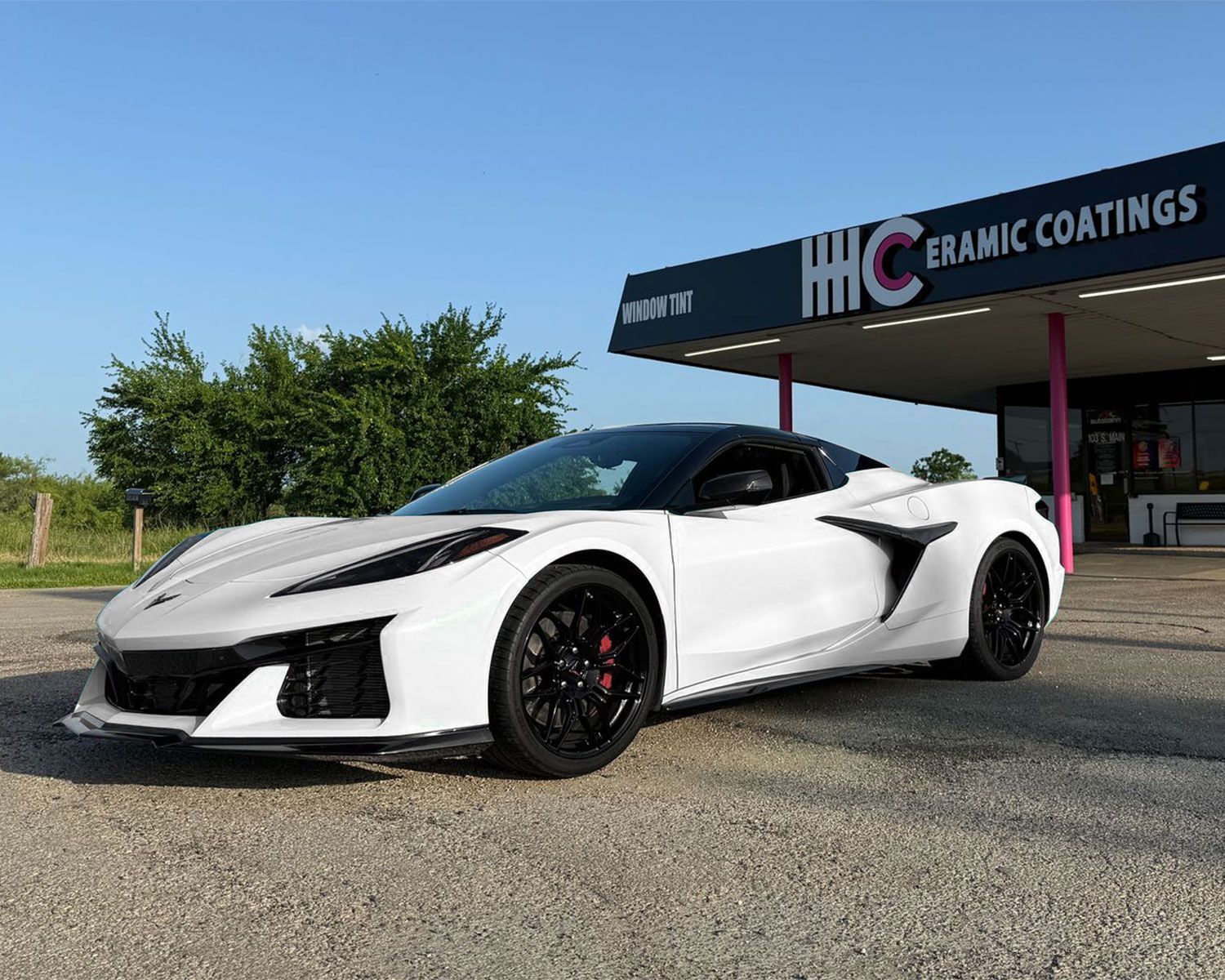 A white sports car is parked in front of a building.