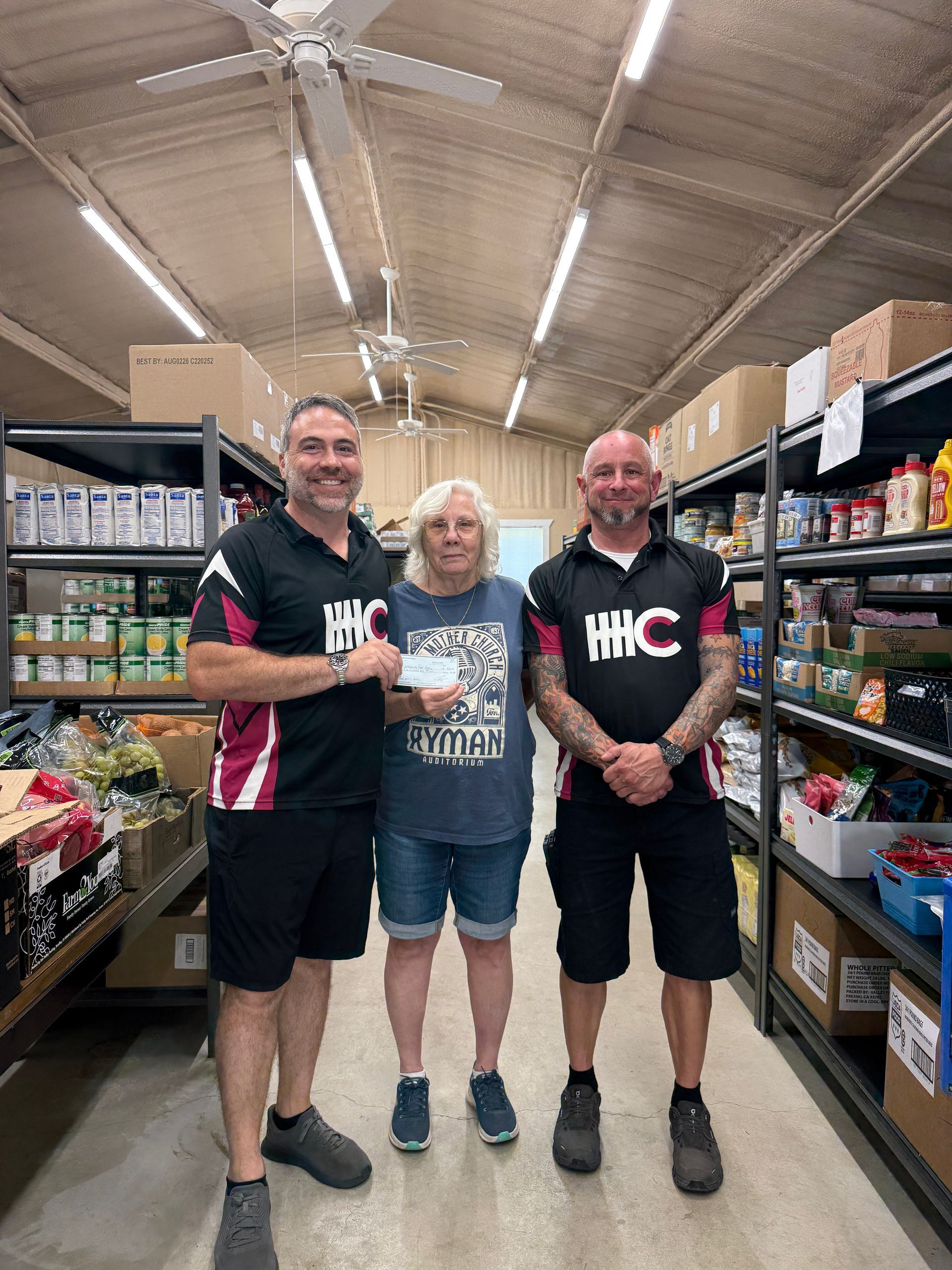 Two men and a girl donate pet food at a shelter.