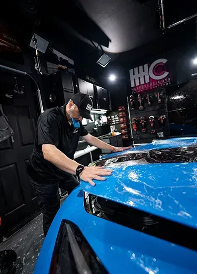 A man is working on a blue car in a garage.