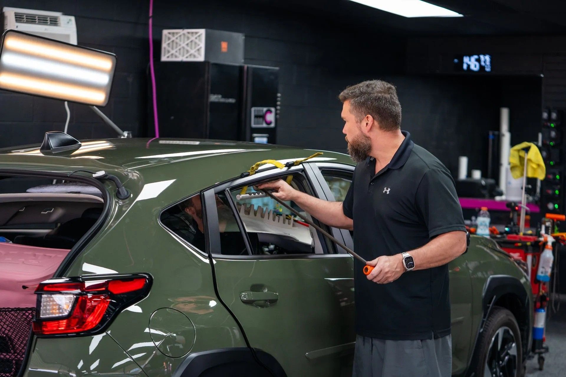 A man is polishing the hood of a red car.