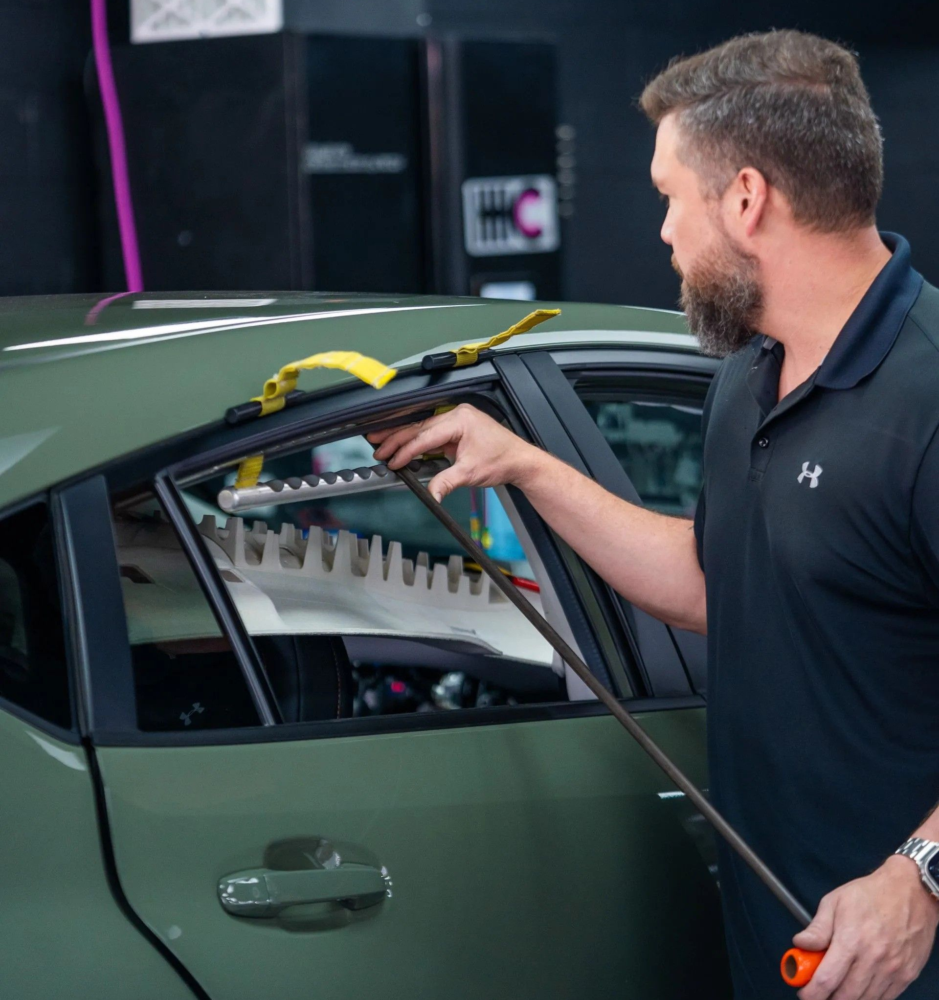 A man is cleaning a red sports car in a garage.