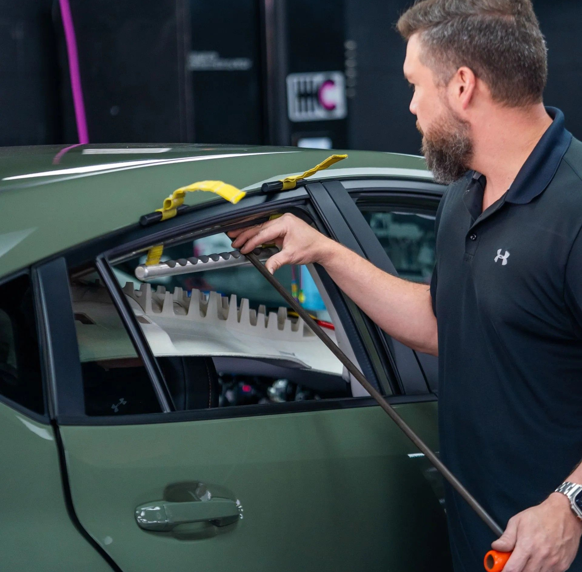 A man is polishing the hood of a red car.
