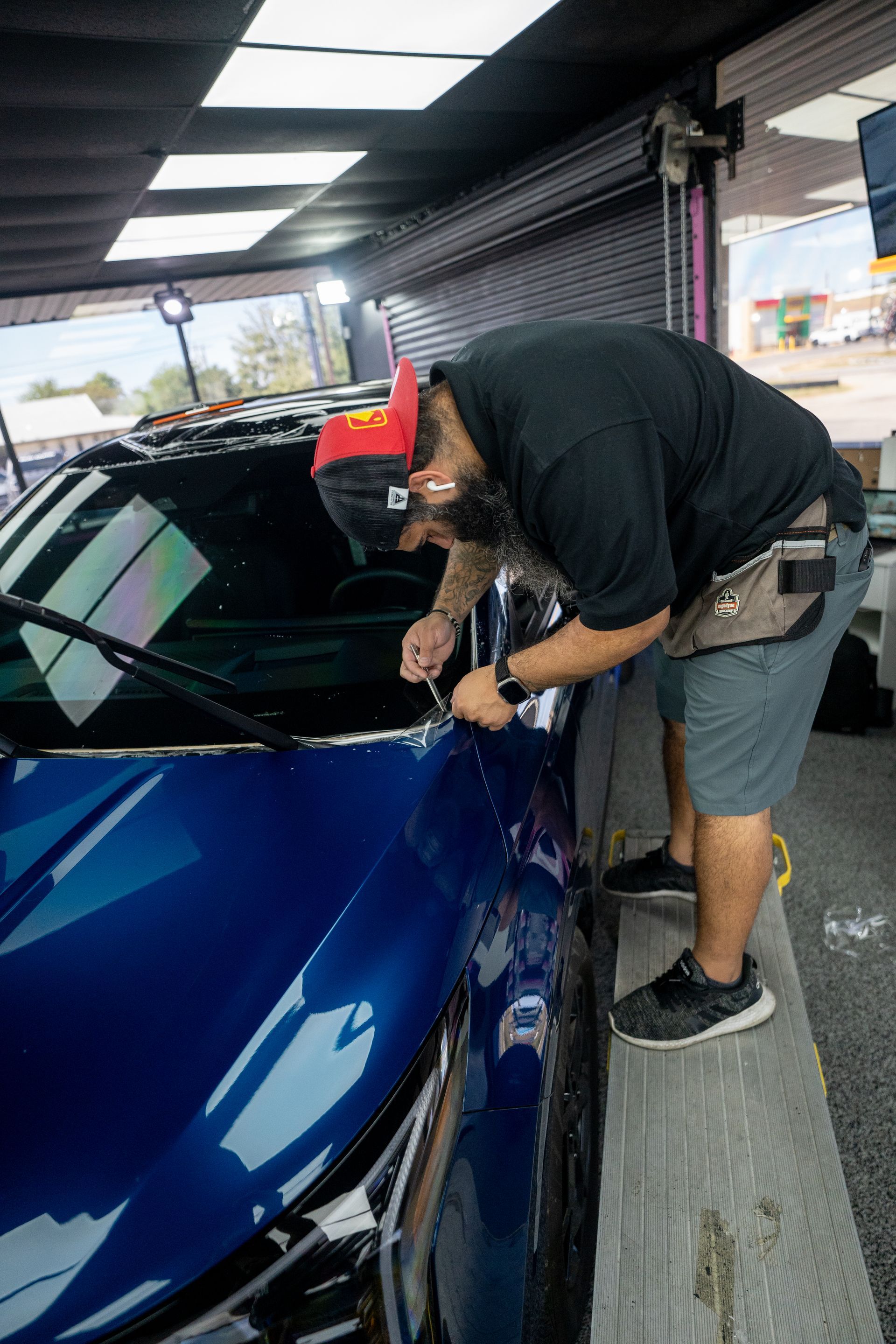 A man is working on a blue car in a car wash.