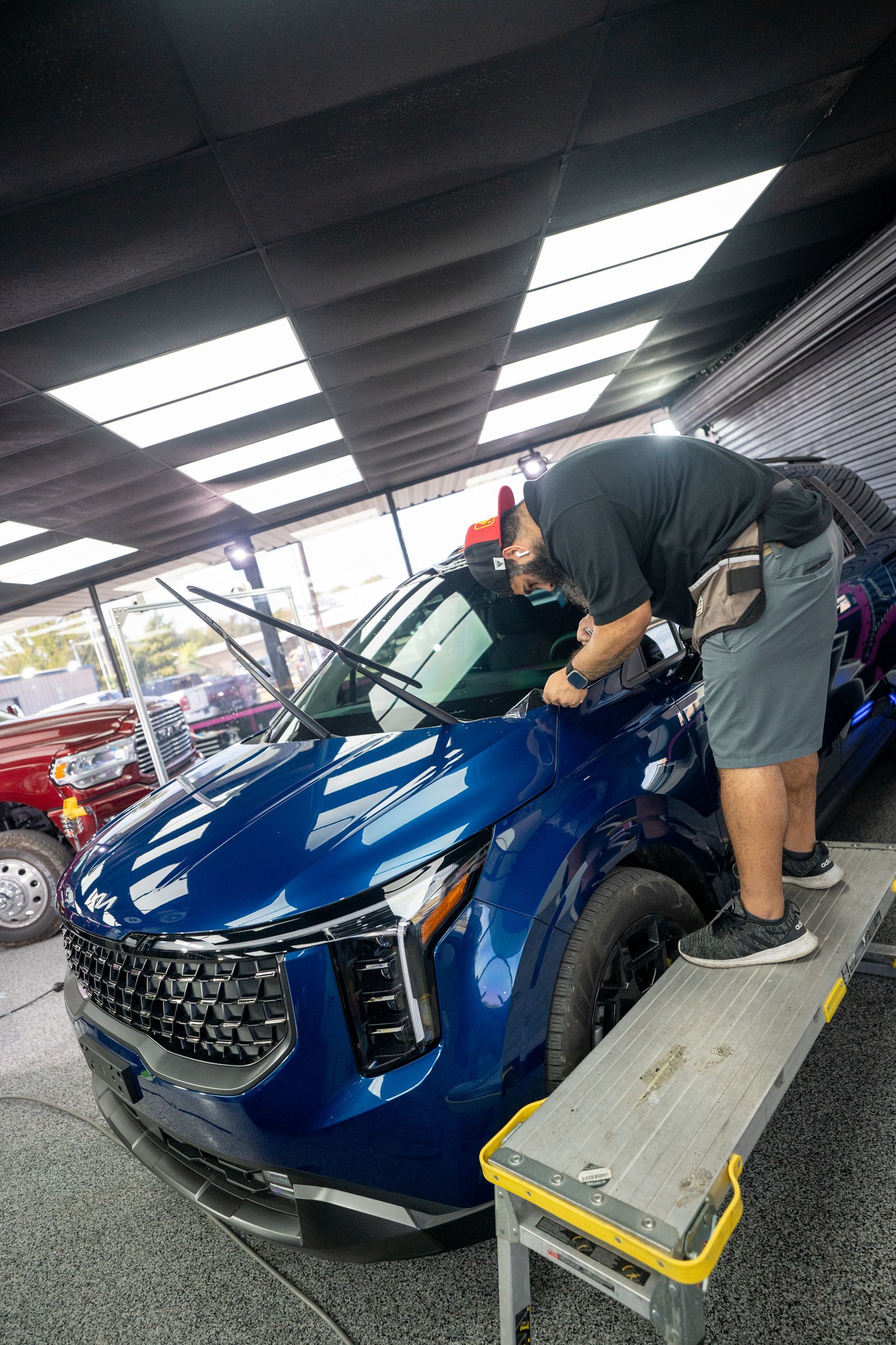 A man is polishing a blue car in a garage.