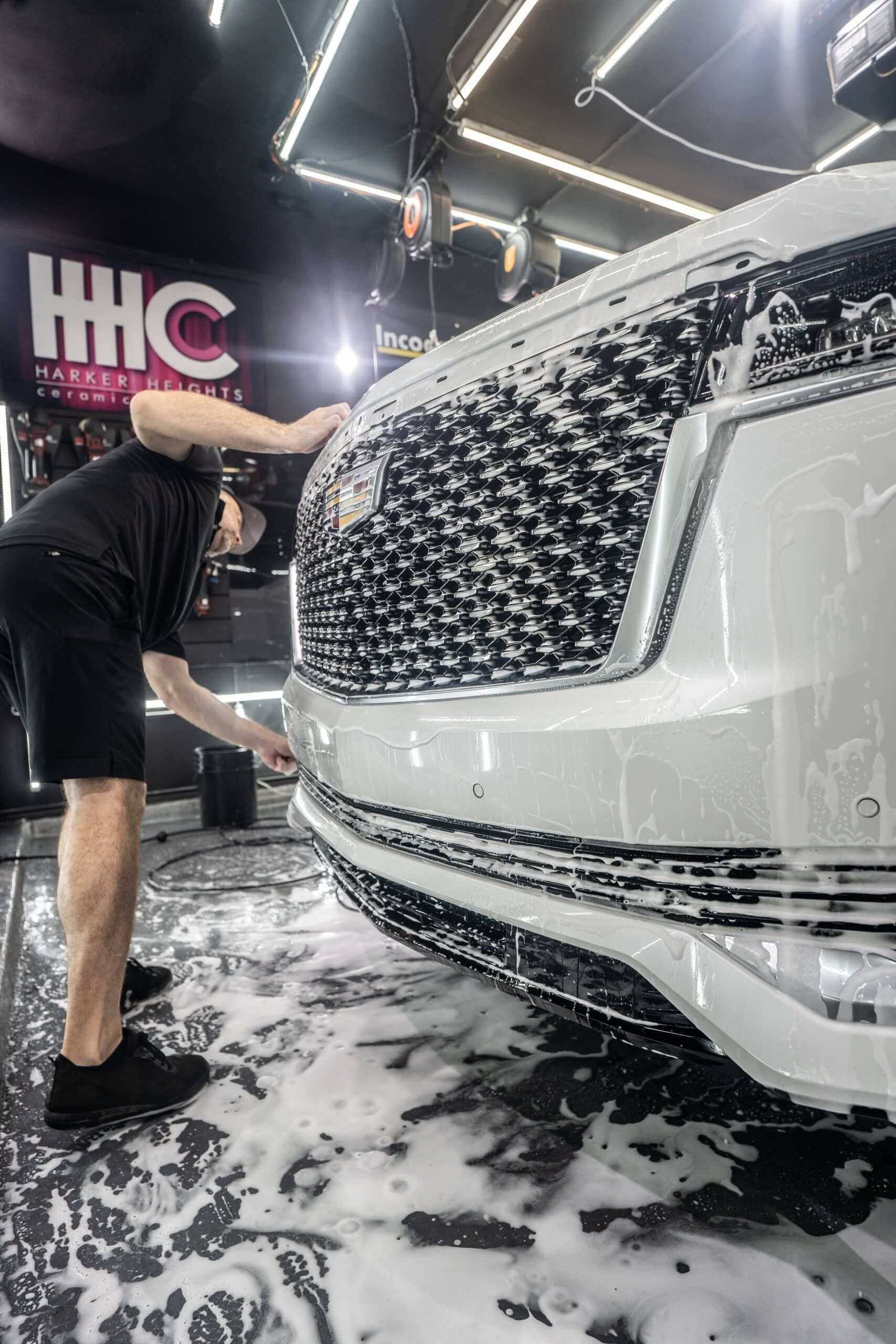 A man is washing a white car in a car wash.