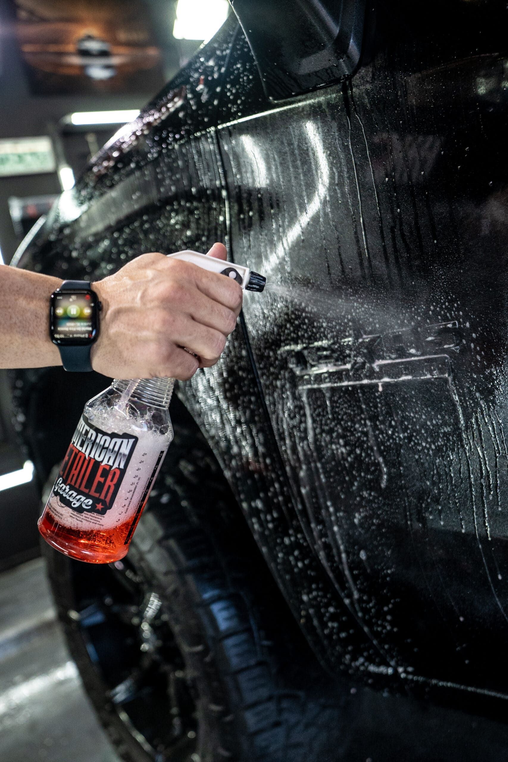 A person is washing a car with a spray bottle.