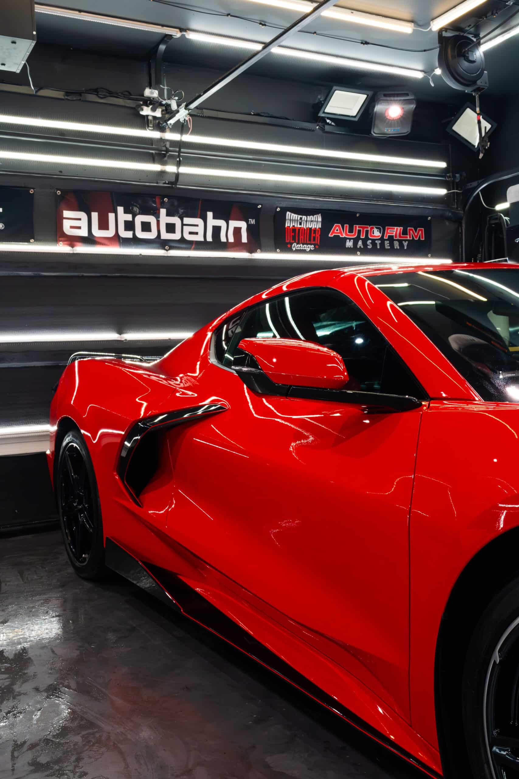 A red sports car is parked in front of a sign that says autobahn
