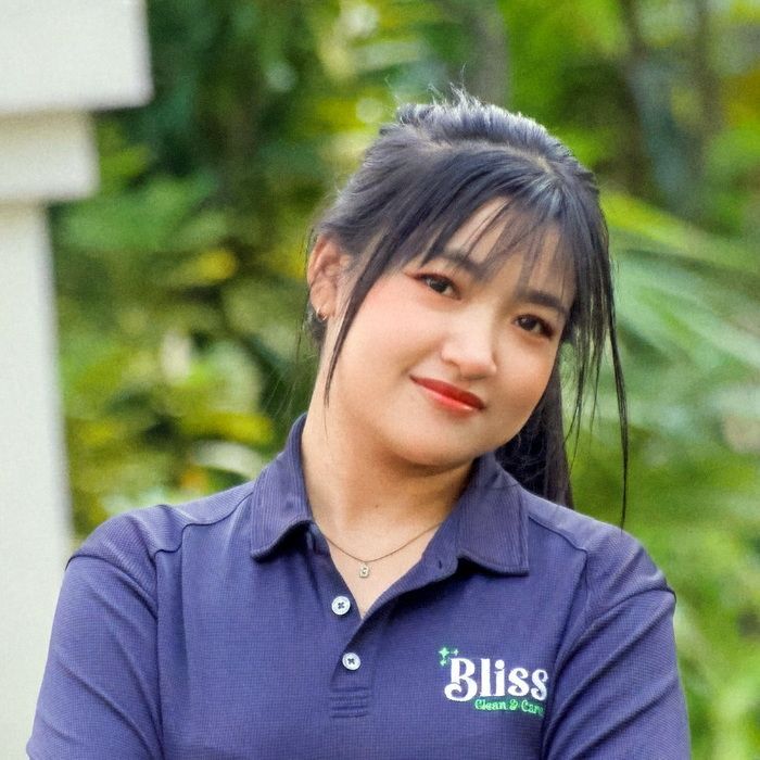 A woman in a green shirt is laughing with her mouth open