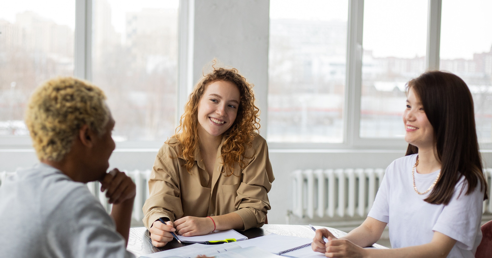 A group of people are sitting around a table having a meeting.