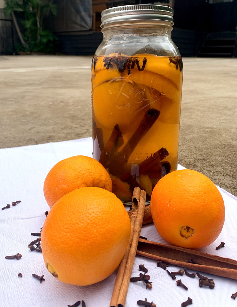 A mason jar filled with oranges and cinnamon sticks