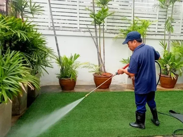 A man is cleaning the side of a house with a high pressure washer.