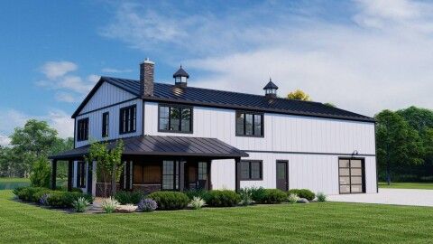 A white house with a black roof is sitting on top of a lush green field.