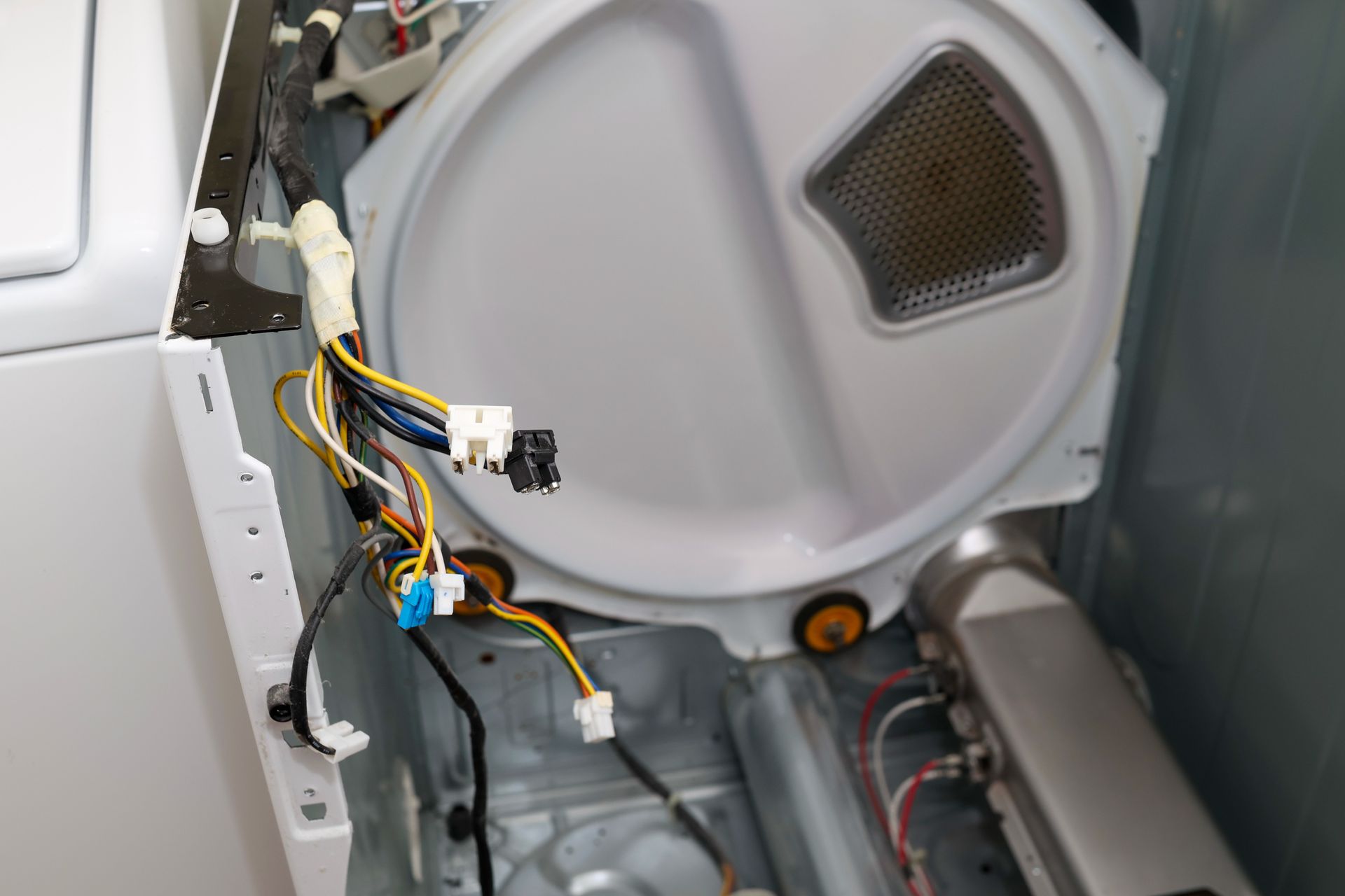 Open washer panel with wiring and components exposed inside a gray appliance Open washer panel with wiring and components exposed inside a gray appliance