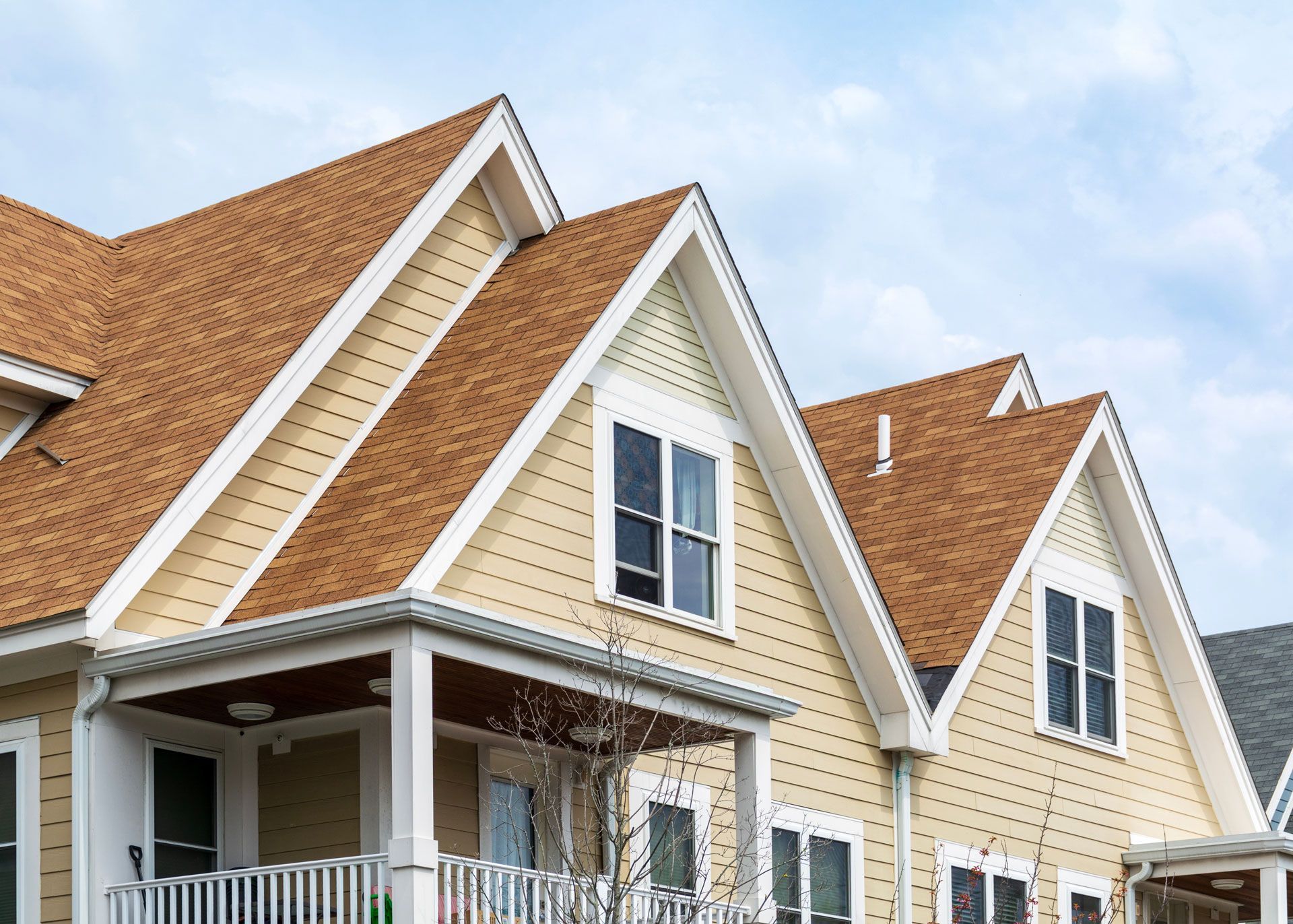 Beige houses with brown roofs against a cloudy sky.