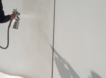Iemand spuit verf op een witte muur.