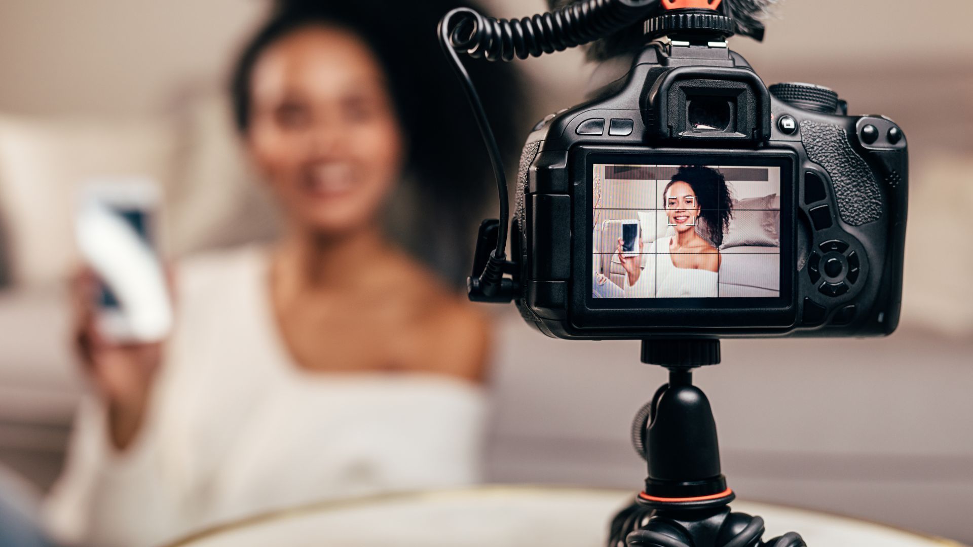 A woman is holding a cell phone in front of a camera.