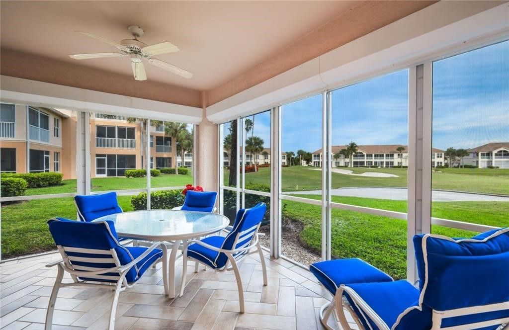 A screened in porch with blue chairs and a table