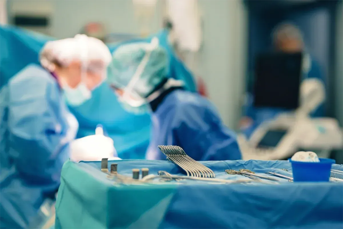Surgical instruments on a table in an operating room; medical staff in scrubs are performing a procedure — Bespoke Legal Group In Northern, NSW