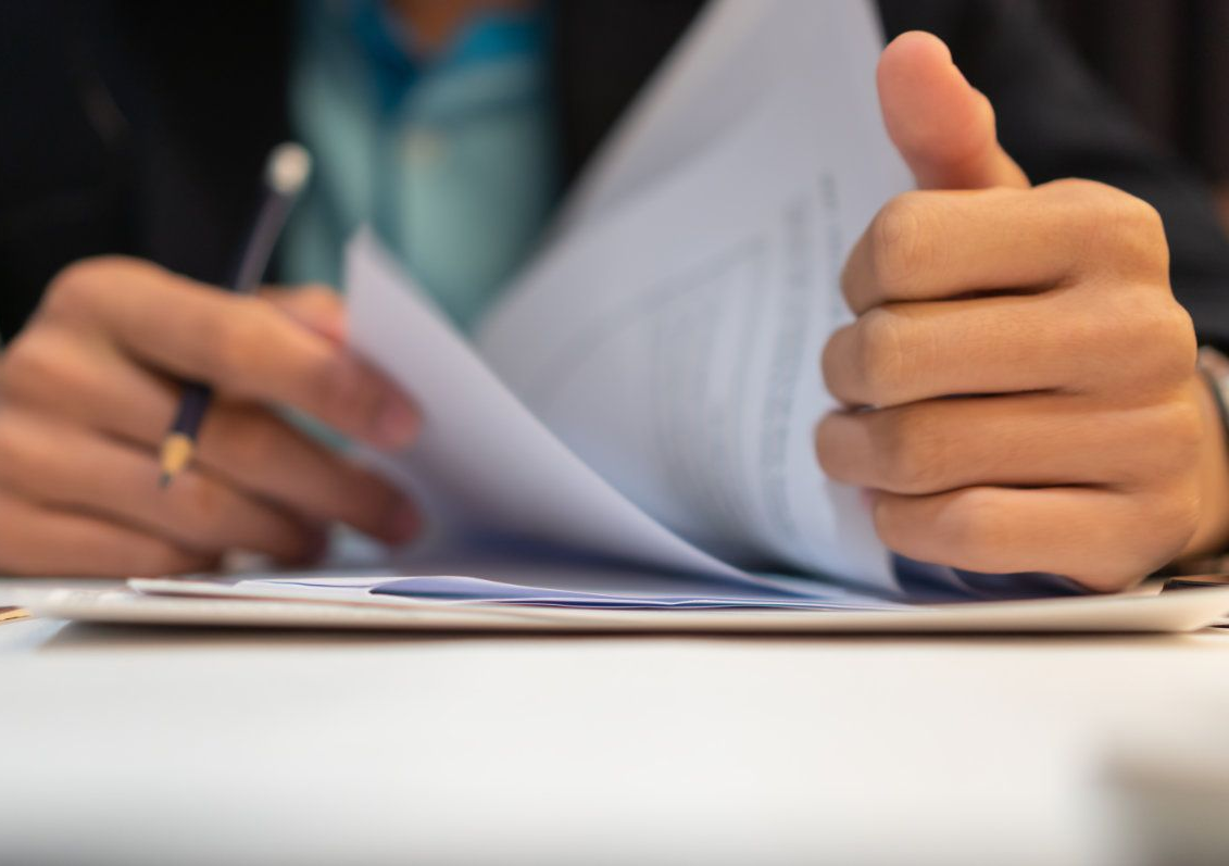 Person reviews documents, holding paper with pen — Bespoke Legal Group In Southport, QLD