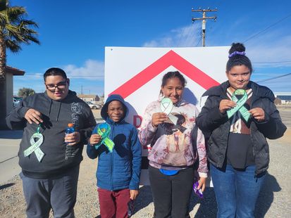 a group of young people are standing in front of a sign holding ribbons .