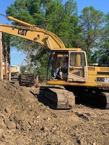 Yellow CAT excavator digging dirt; operator inside.