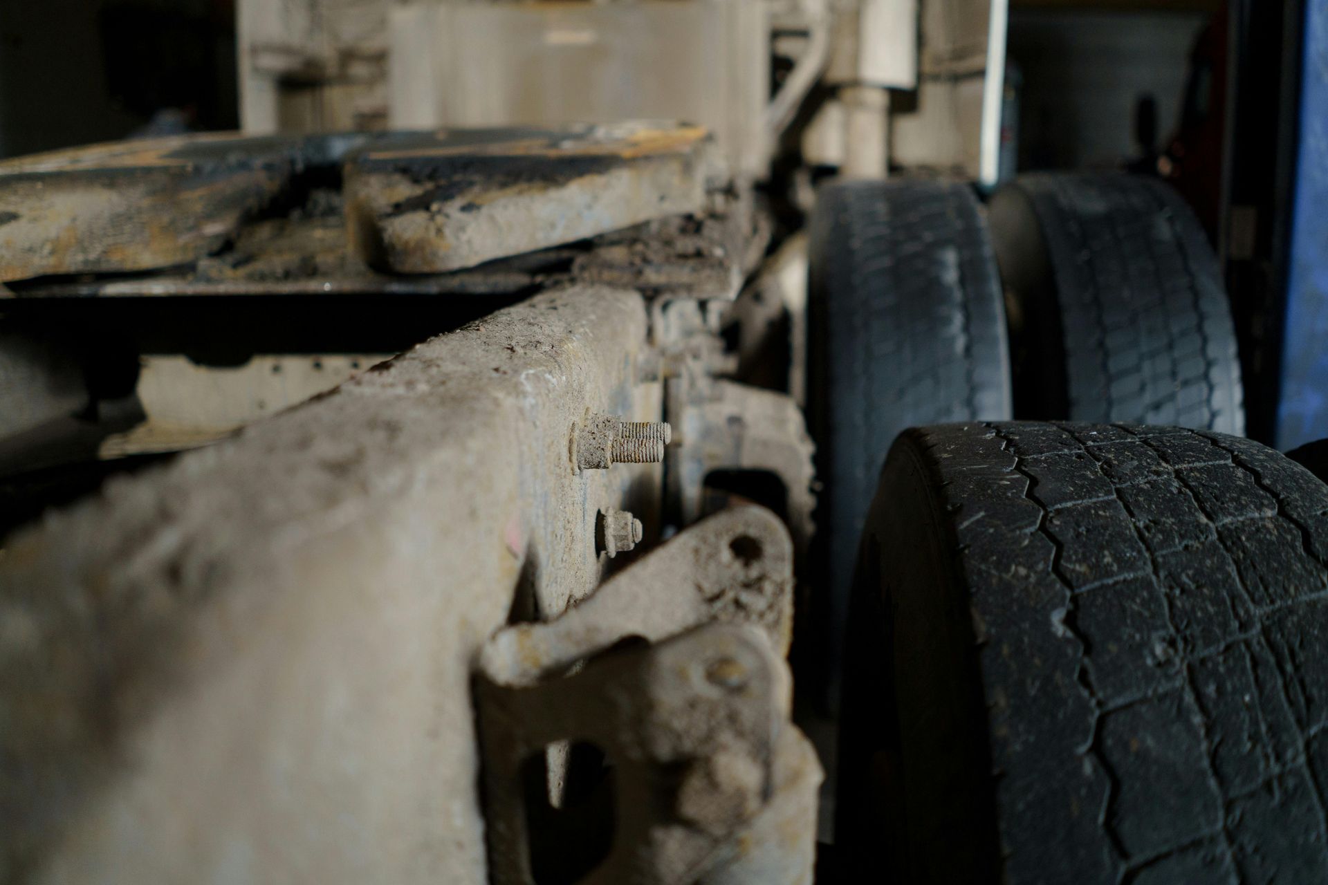 Close-up of a truck's dirty undercarriage, showing tires, metal frame, and coupling area.