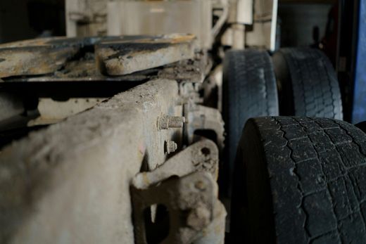 Close-up of a truck's dirty undercarriage, showing tires, metal frame, and coupling area.