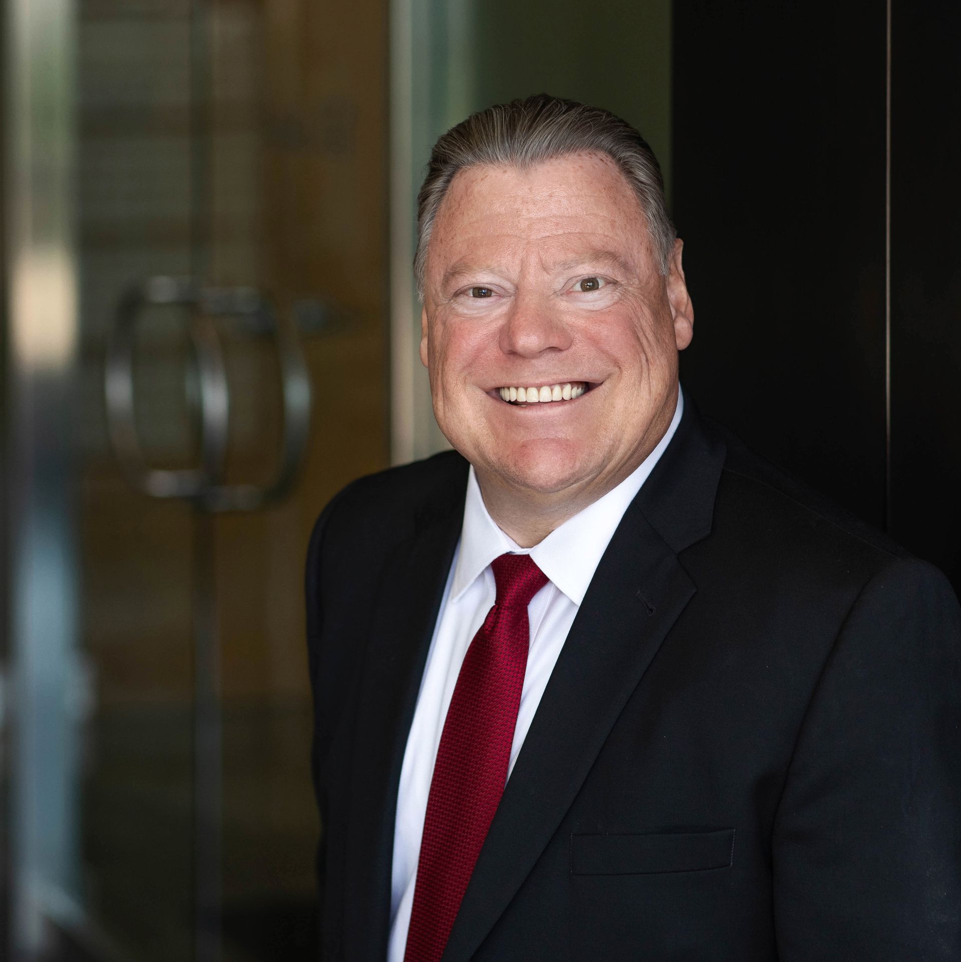 A man in a suit and tie is smiling for the camera