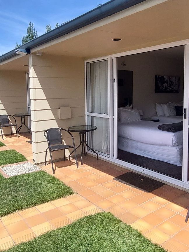 There is a patio with a table and chairs in front of a bedroom.
