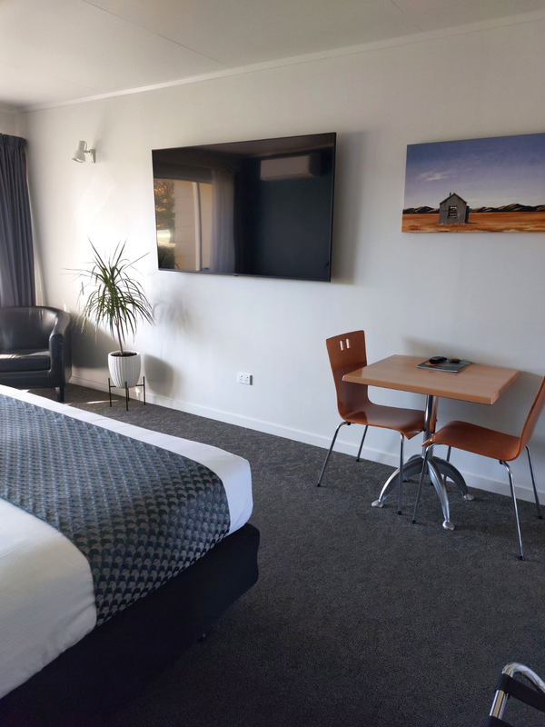 A quality motel room with a Super king bed, and doors opening up to a lawn and view over Cromwell Golf Course.