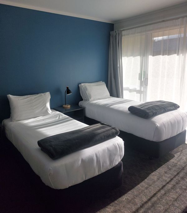 A hotel room with a bed , chair , lamp and blue walls.