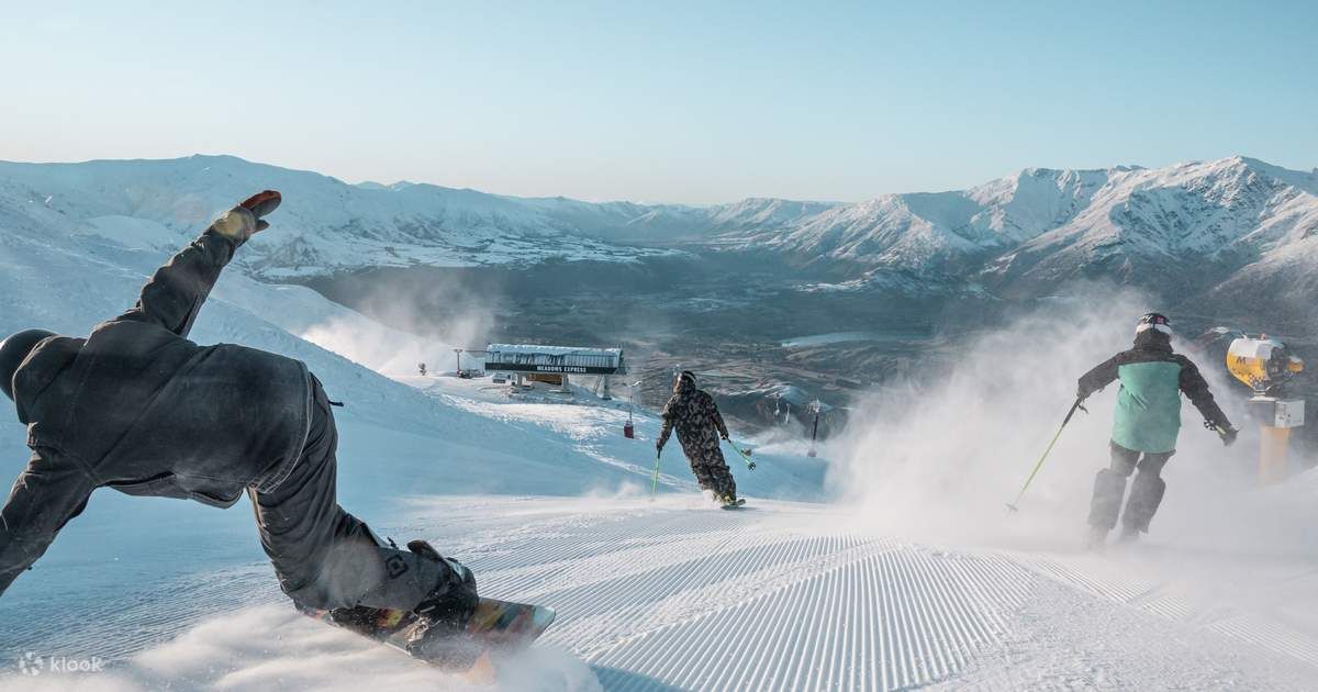 Skiers and snowboarders carving through fresh powder on the slopes of Coronet Peak Ski Field
