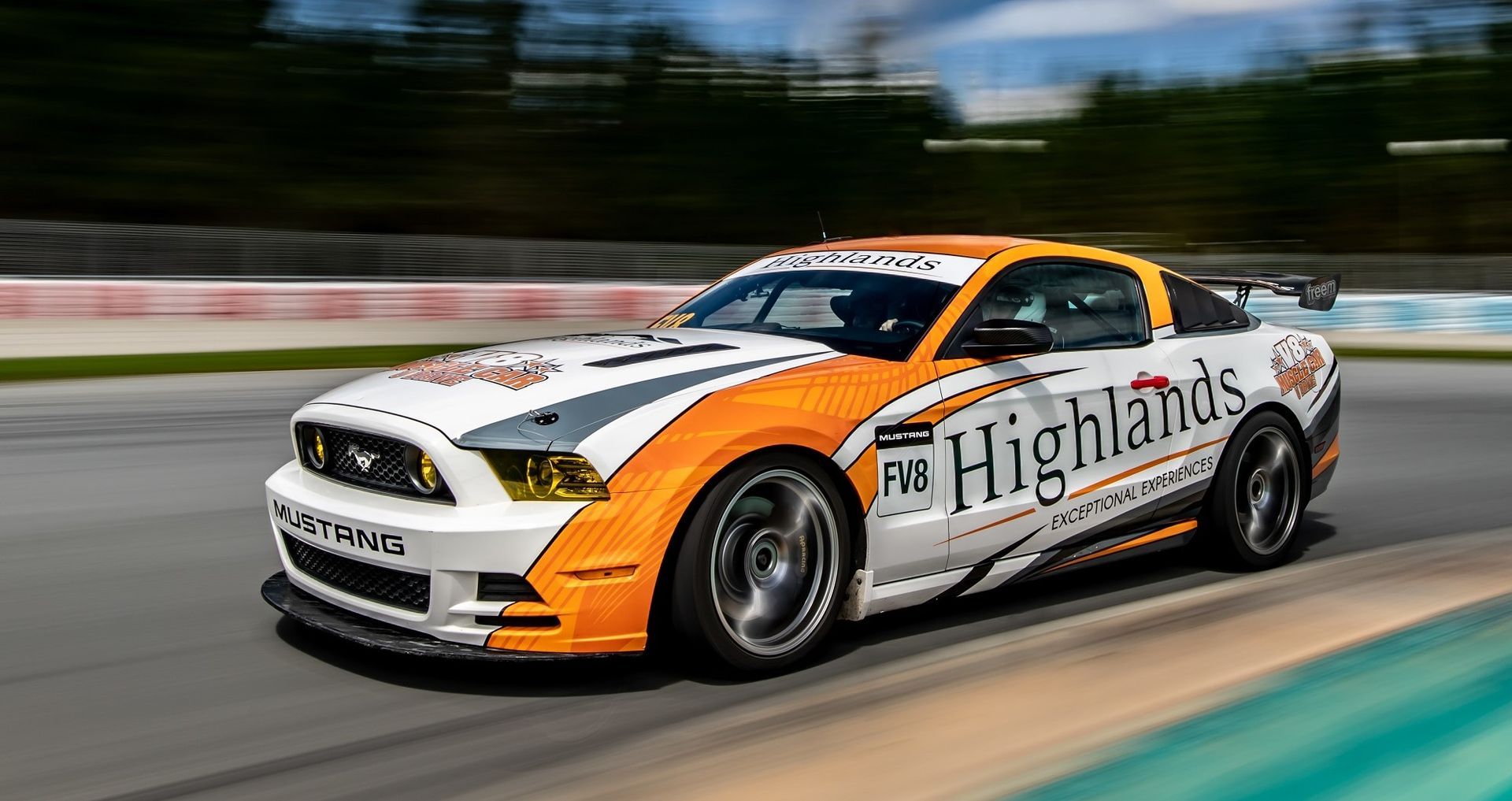Enthusiastic drivers revving up Mustangs at the Highland Race Track for an exhilarating u-drive experience, with sleek cars