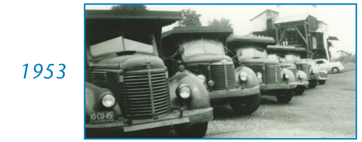 A black and white photo of a row of trucks from 1953 A black and white photo of a row of trucks from 1953