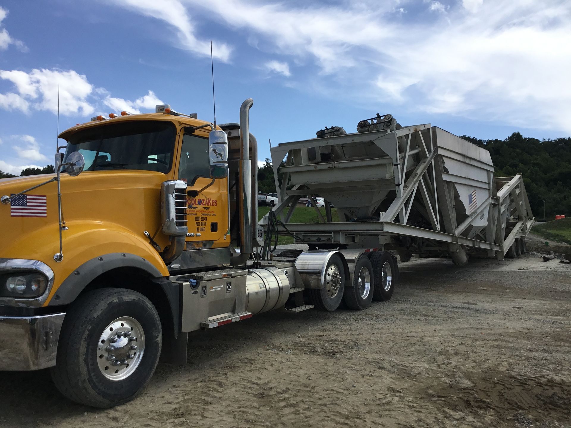 A semi truck is carrying a yellow bulldozer on a trailer.