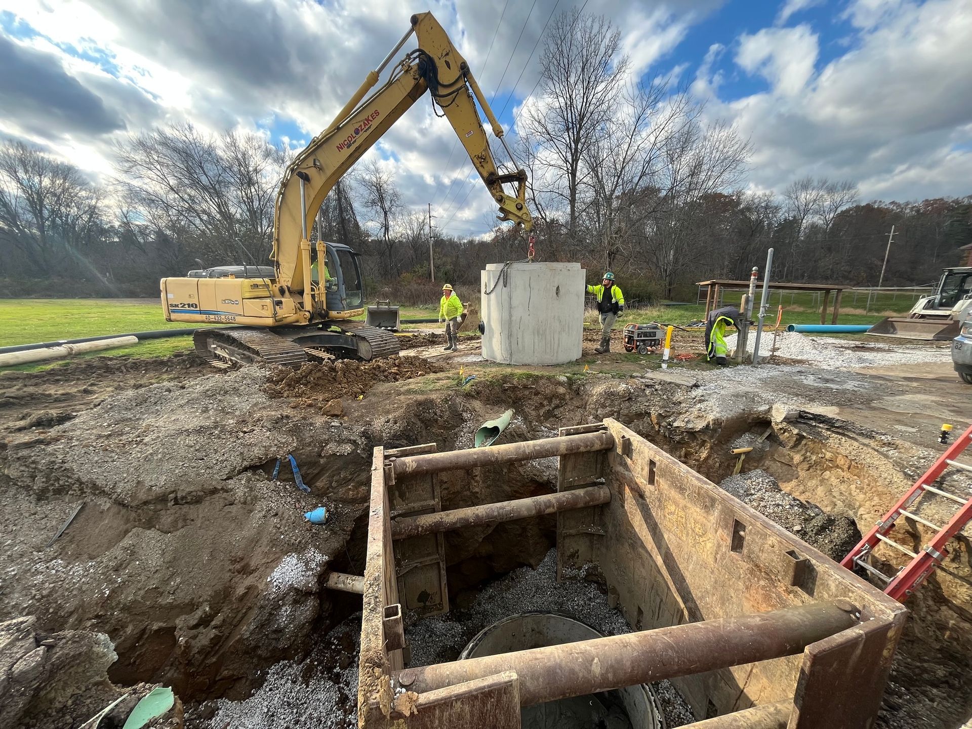 Two construction workers are looking at a laptop while standing next to a car.