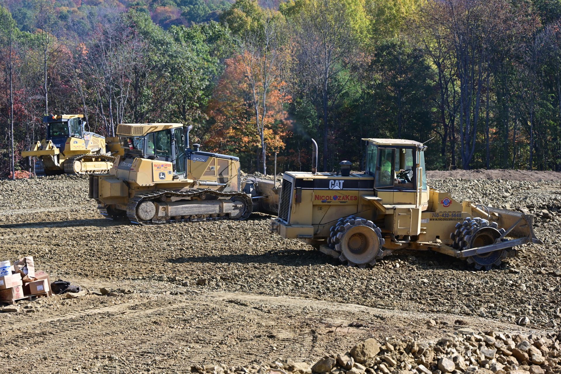Two construction workers are standing in front of a bulldozer on a construction site.