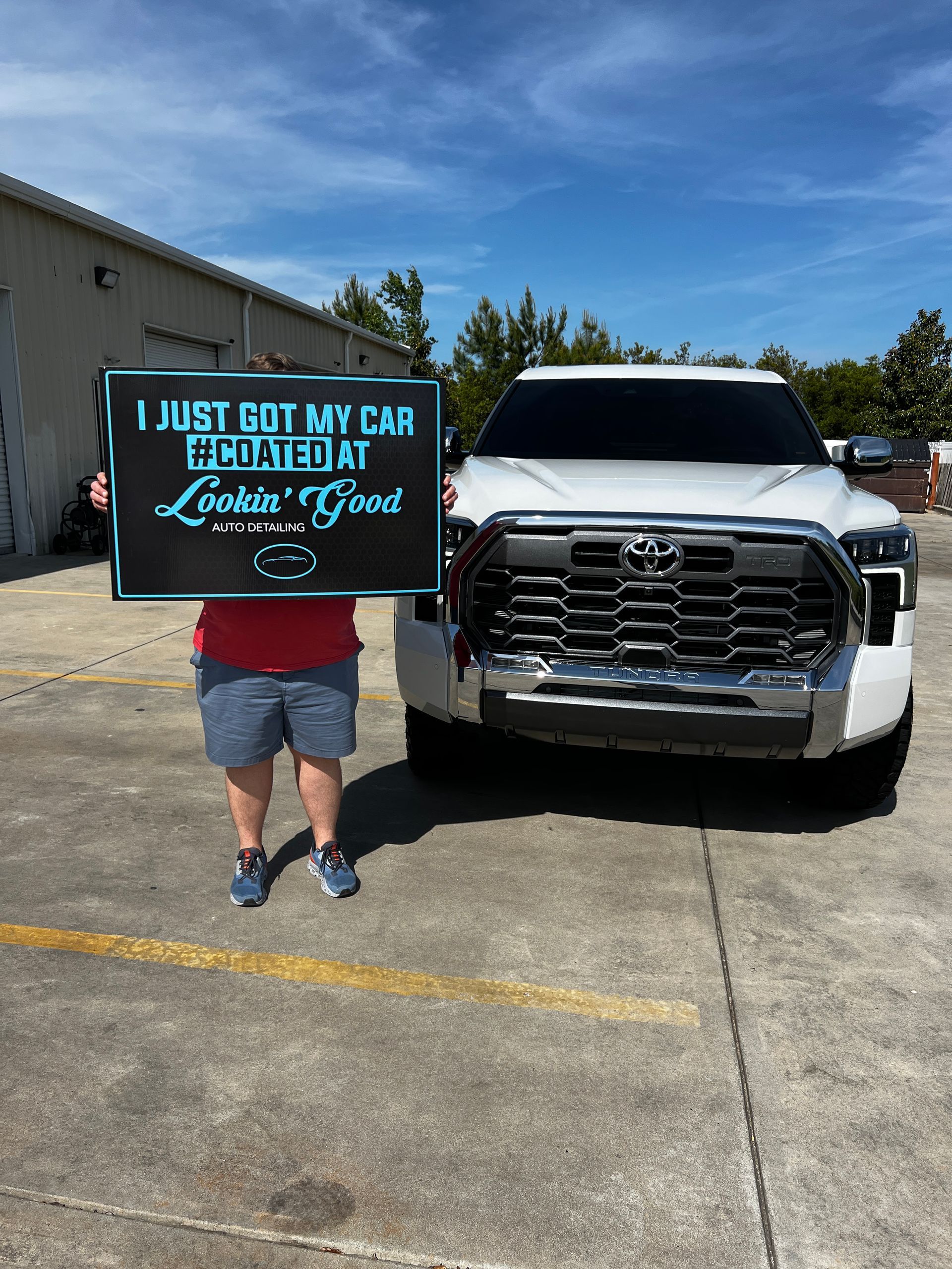 Person holding a sign in front of a white Toyota truck; text reads 