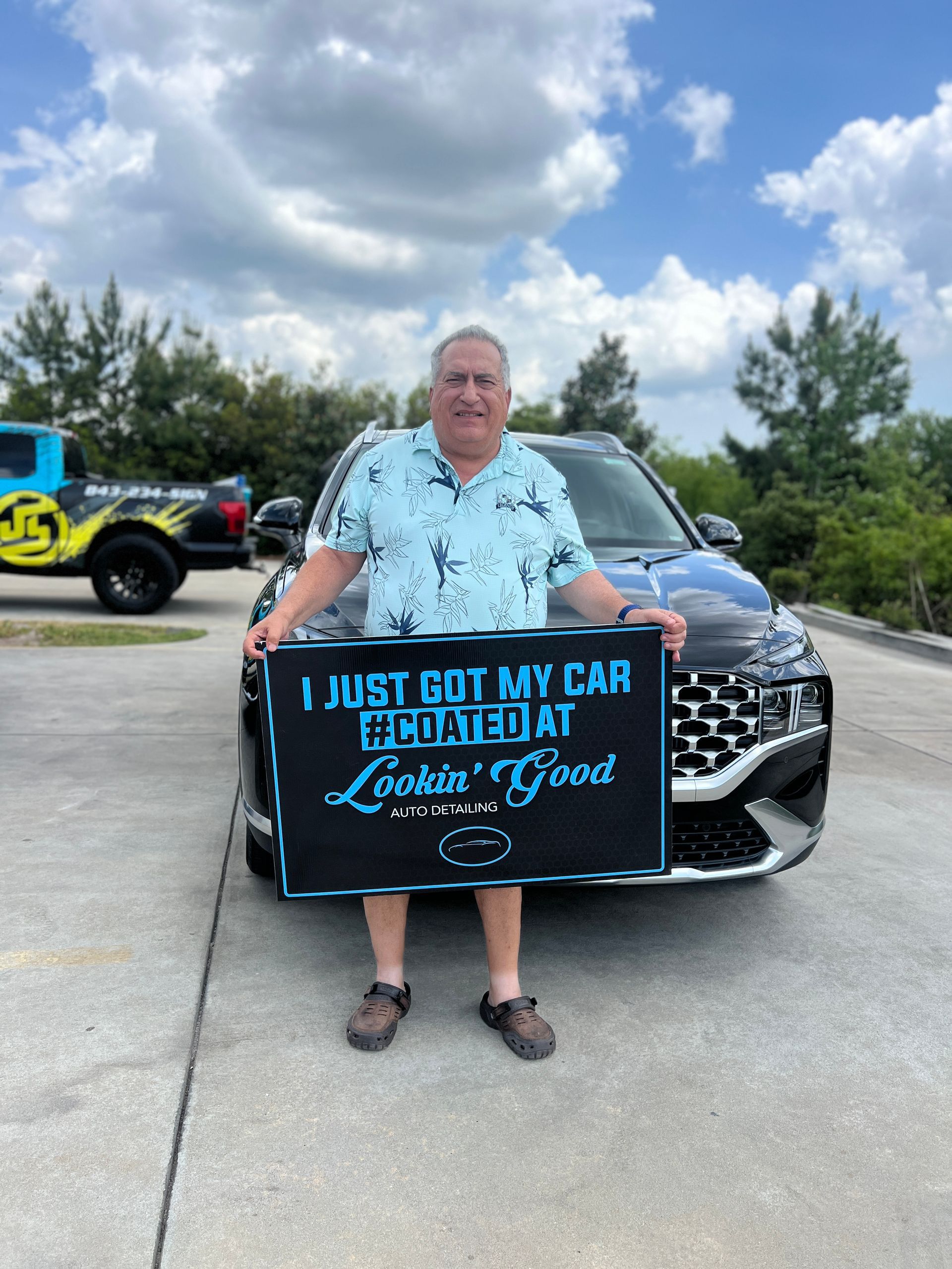 Man holding a sign in front of a black SUV. Sign reads, 