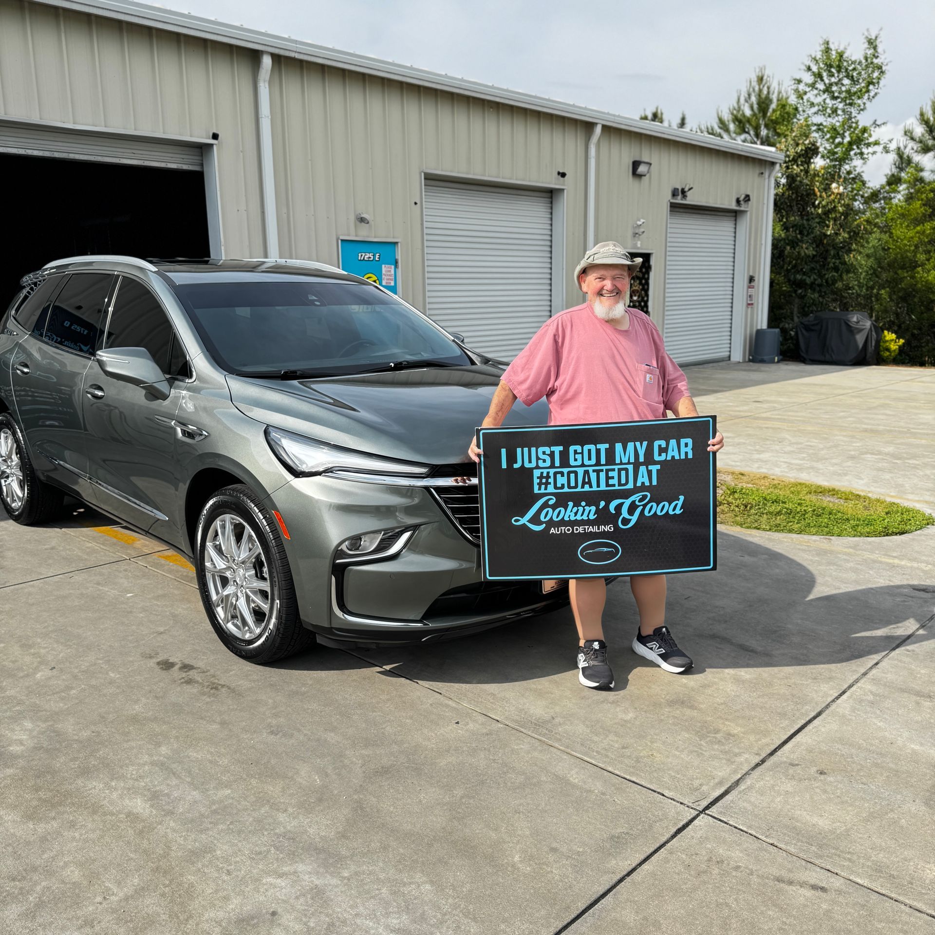 Man standing with new gray SUV, holding sign: 