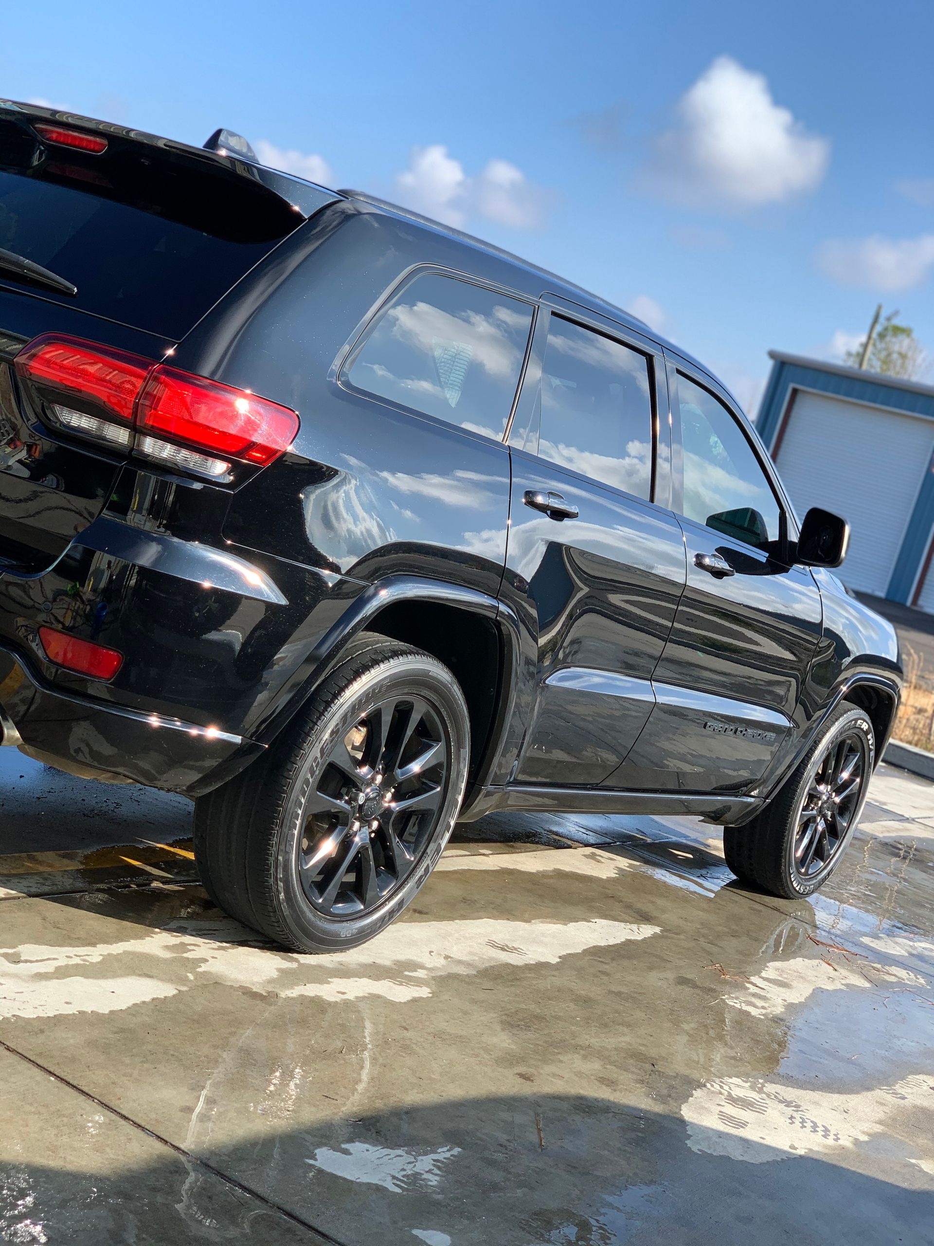 A black jeep grand cherokee is parked in a parking lot.
