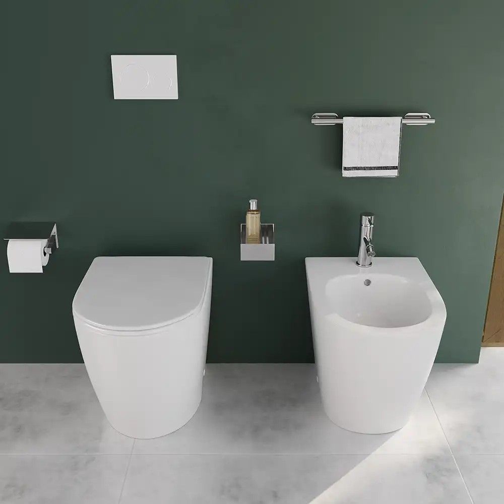Bagno moderno con WC, bidet e accessori bianchi contro una parete verde scuro.
